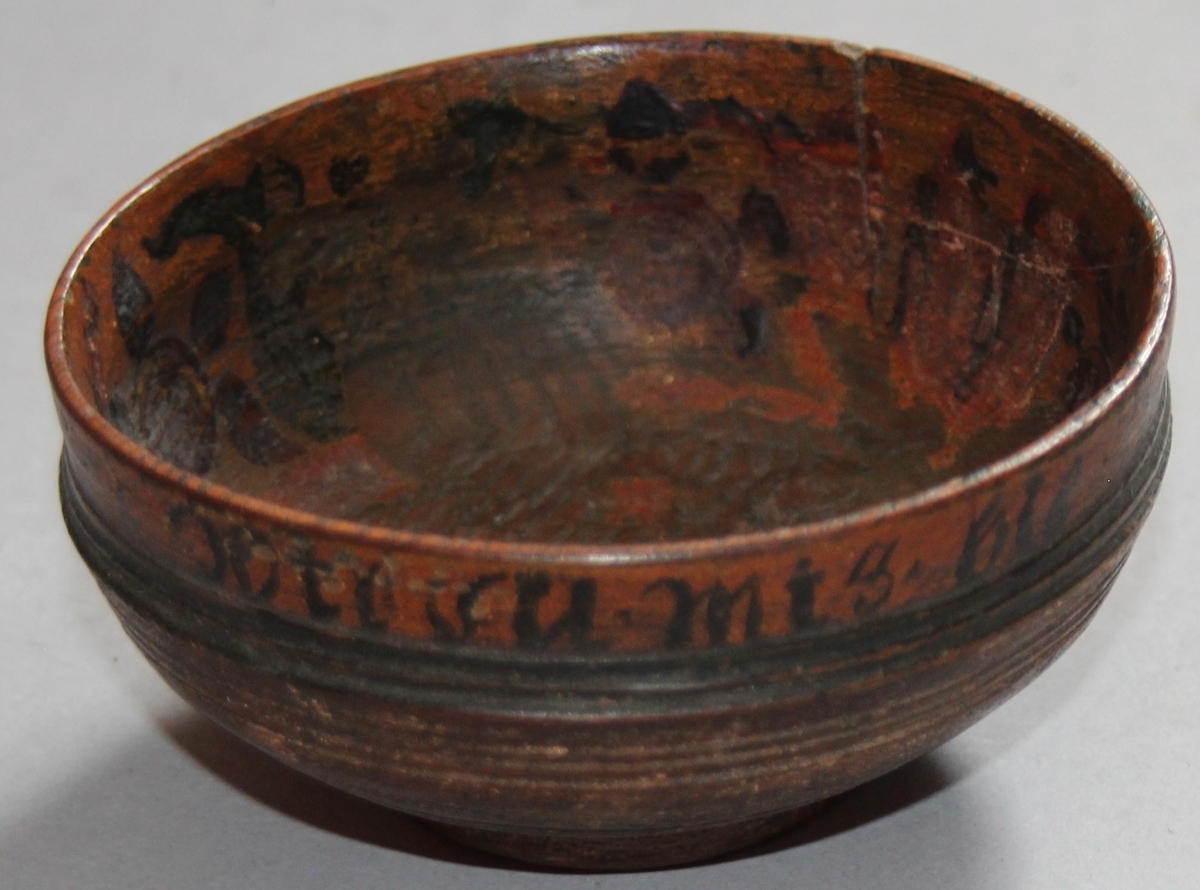 Liten dreia bolle. Rosemåla med tekst kring kanten på utsida. Teksten er utydleg men det kan lesast "R.O.S.1775 sett(?) nu mig bie(?) snart får du rusen føle" Rosemåling inni bollen, blad og blomstermotiv. Rosemålinga er noko slitt. Utanpå er bollen brunmåla, med ei grøn stripe og orange kant. Bollen har ein skade på den eine sida. denne skaden er lima.