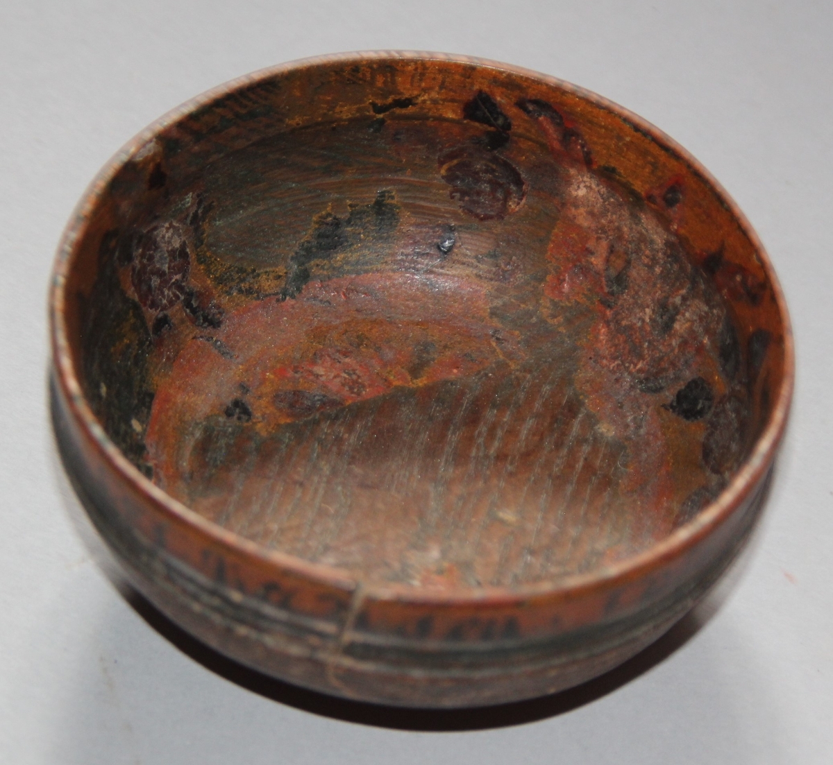 Liten dreia bolle. Rosemåla med tekst kring kanten på utsida. Teksten er utydleg men det kan lesast "R.O.S.1775 sett(?) nu mig bie(?) snart får du rusen føle" Rosemåling inni bollen, blad og blomstermotiv. Rosemålinga er noko slitt. Utanpå er bollen brunmåla, med ei grøn stripe og orange kant. Bollen har ein skade på den eine sida. denne skaden er lima.