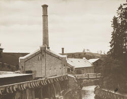 Bygning i teglstein med høy pipe. Mulig tresliperi?