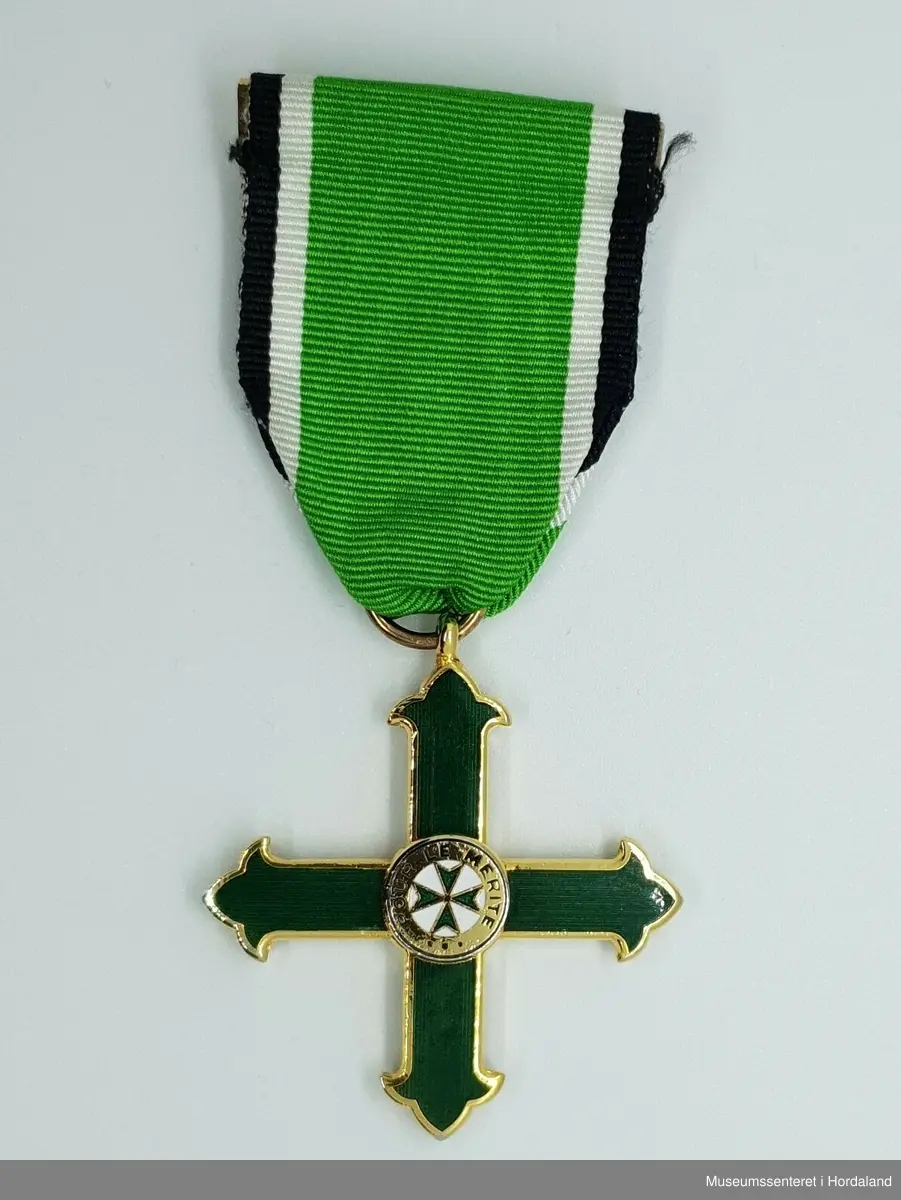 Medaljen er formet som et likearmet kors der armene er avsluttet med en liljeform. Korset senter er dekket av en sirkel med tekst som omkranser et lite grønt toflike likeamet kors på hvit bunn. 