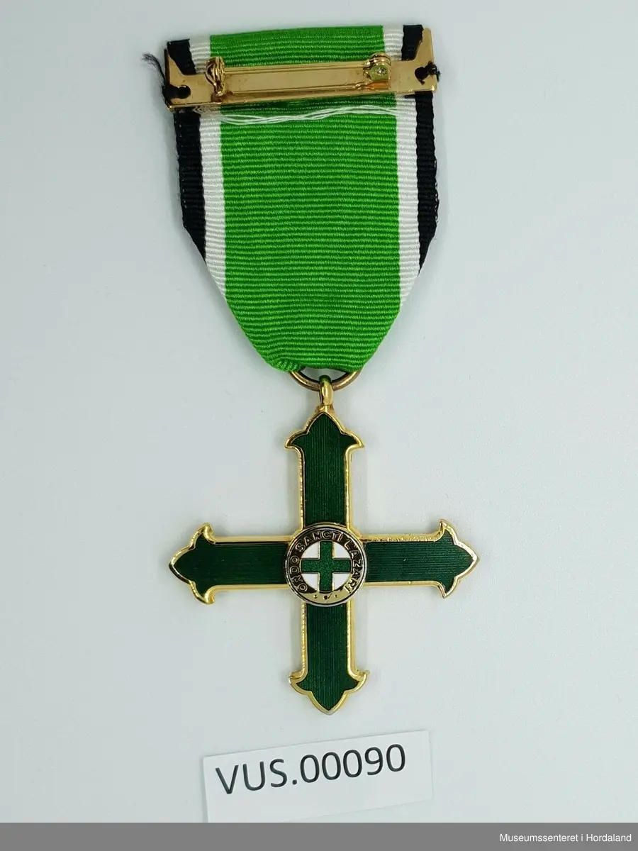 Medaljen er formet som et likearmet kors der armene er avsluttet med en liljeform. Korset senter er dekket av en sirkel med tekst som omkranser et lite grønt toflike likeamet kors på hvit bunn. 