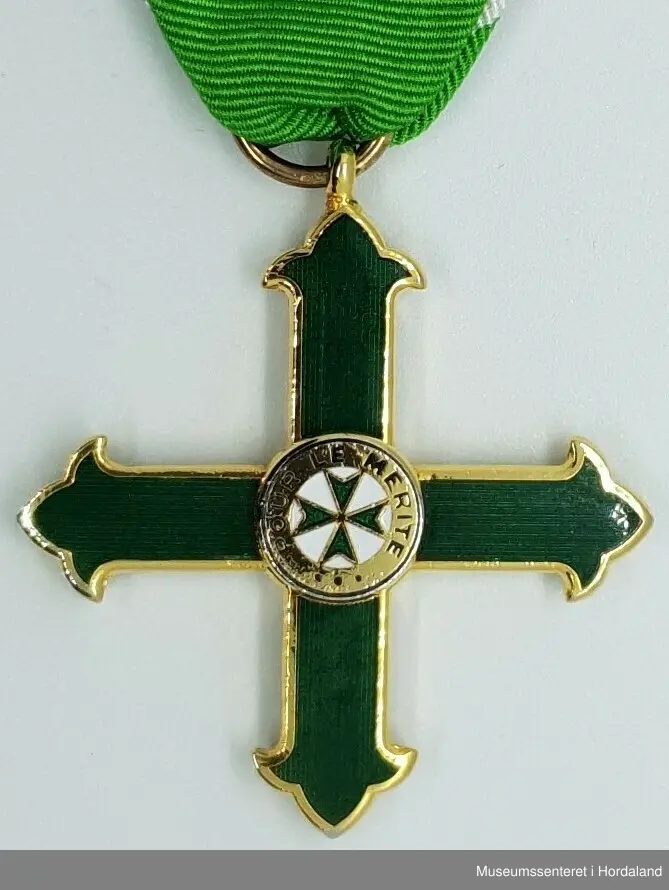 Medaljen er formet som et likearmet kors der armene er avsluttet med en liljeform. Korset senter er dekket av en sirkel med tekst som omkranser et lite grønt toflike likeamet kors på hvit bunn. 