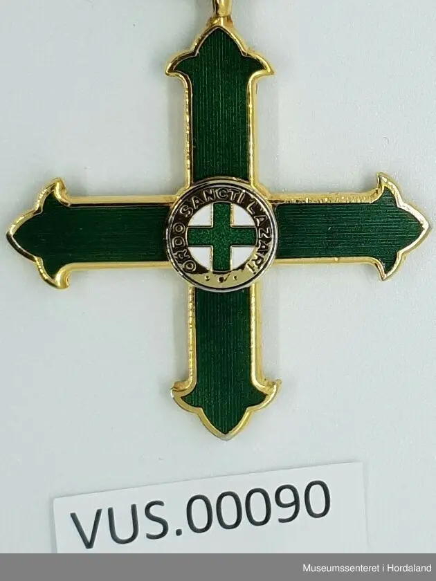 Medaljen er formet som et likearmet kors der armene er avsluttet med en liljeform. Korset senter er dekket av en sirkel med tekst som omkranser et lite grønt toflike likeamet kors på hvit bunn. 