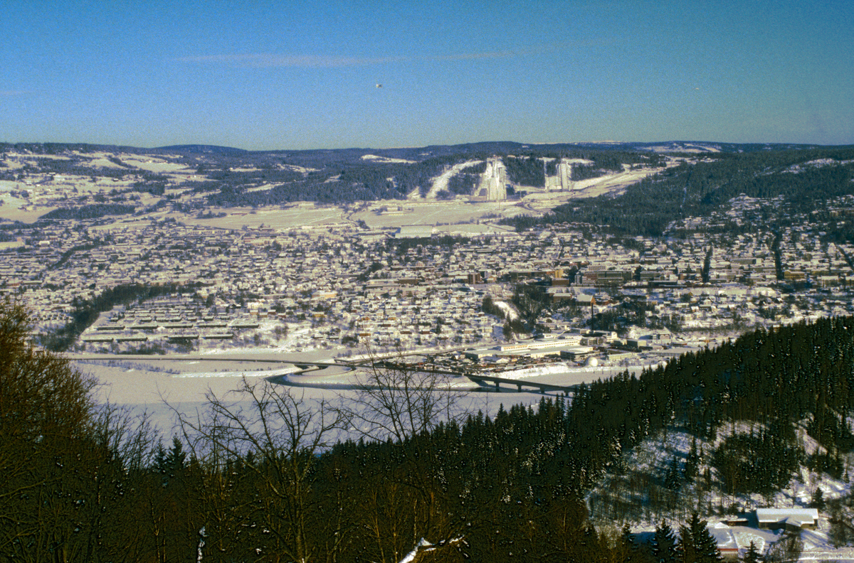 Lillehammer by under OL 1994. OL-parken med Lysgårdsbakkene hoppanlegg og Kanthaugen freestyleanlegg i bakgrunnen. CBS's luftskip ses på himmelen. Utsikt mot øst fra Saksumsdalsvegen.