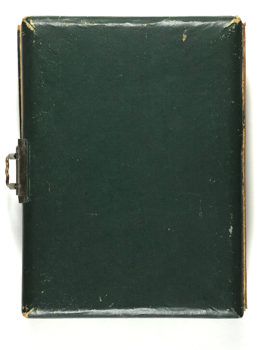Svarthvitt-fotos i album med mørkegrønn skinnimitert perm og metallspenne.
