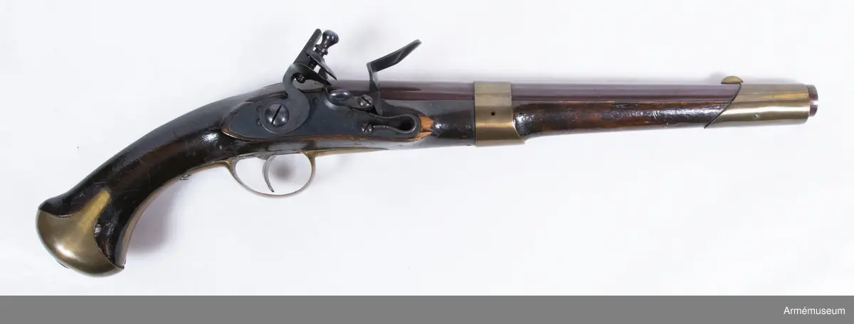 Pistol med flintlås.
Pipan är brungjord. Låset är blånerat. Pistolen har mässingsbeslag utom ryggbeslaget på kolven, vilket är av järn. På pipans kammarstycke finns en stämpel "Helvig inv.t" Kolven är märkt "I S", på vänster sida ovanför sidblecket.