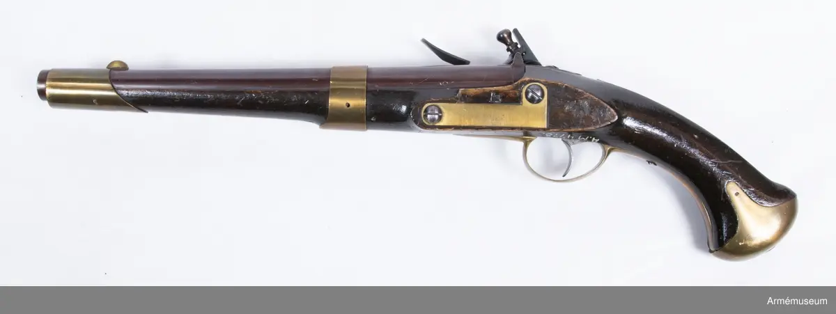 Pistol med flintlås.
Pipan är brungjord. Låset är blånerat. Pistolen har mässingsbeslag utom ryggbeslaget på kolven, vilket är av järn. På pipans kammarstycke finns en stämpel "Helvig inv.t" Kolven är märkt "I S", på vänster sida ovanför sidblecket.