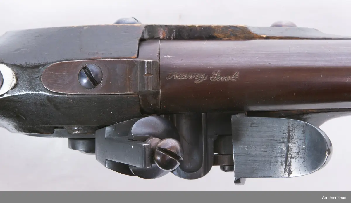 Pistol med flintlås.
Pipan är brungjord. Låset är blånerat. Pistolen har mässingsbeslag utom ryggbeslaget på kolven, vilket är av järn. På pipans kammarstycke finns en stämpel "Helvig inv.t" Kolven är märkt "I S", på vänster sida ovanför sidblecket.