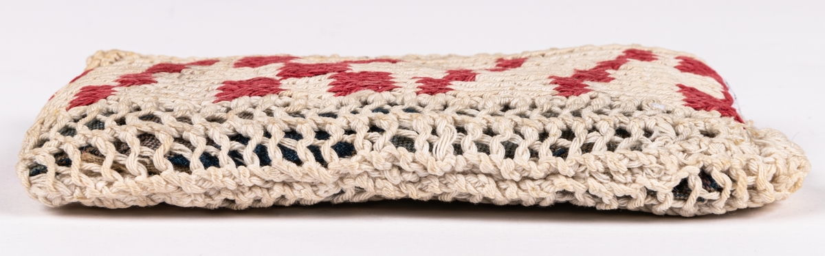 Dyna, till docka.
Stickad remsa med röda rutor. Hopsydd med flätsöm. Fylld innerdyna.
Mönsterstickad med vitt och rött bomullsgarn. Blåvitt bomullstyg och fyllning.