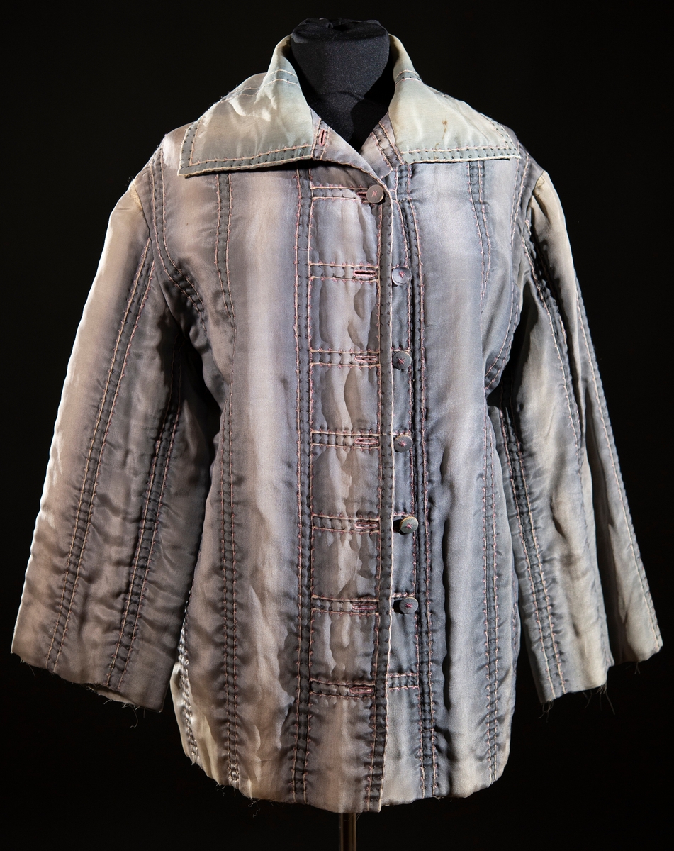 Av blågrått siden. Handbroderad med rosa och svart silke. Handtryckt sidenfoder med blom- och bladmotiv.