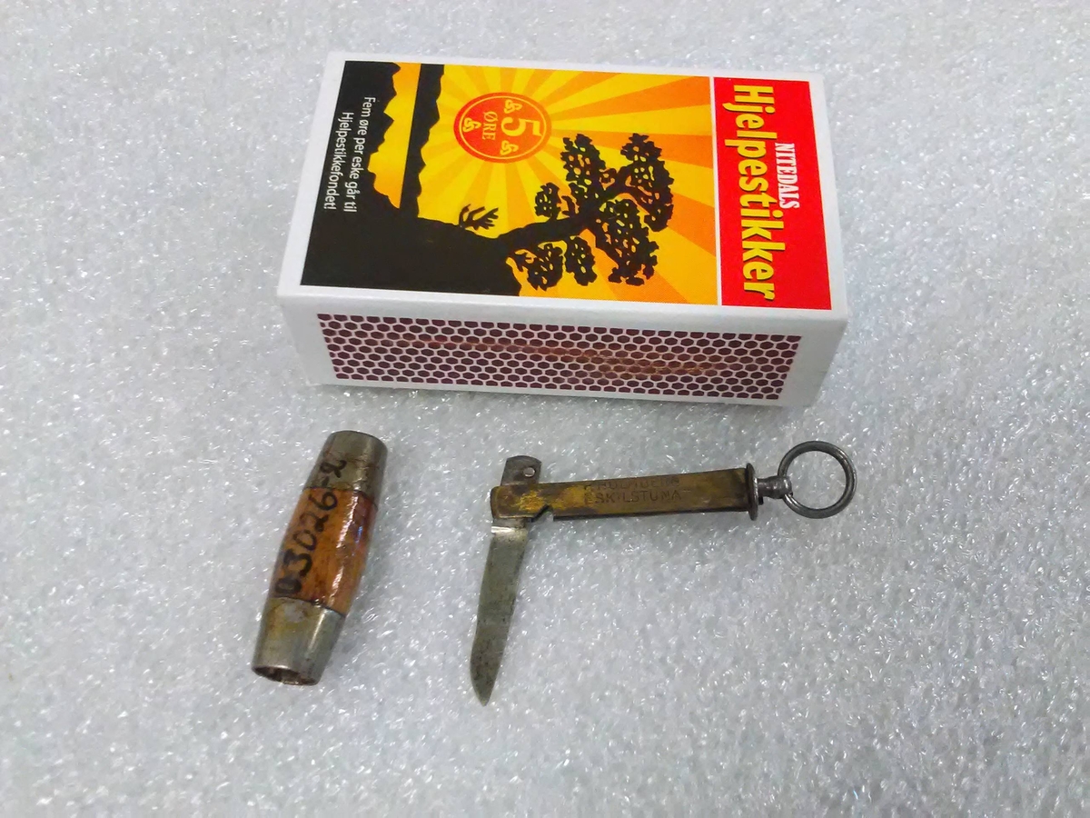 Liten sammenleggbar kniv i stål og messing med oval slire i tre og metall. Metallring til å trekke kniven ut av sliren.