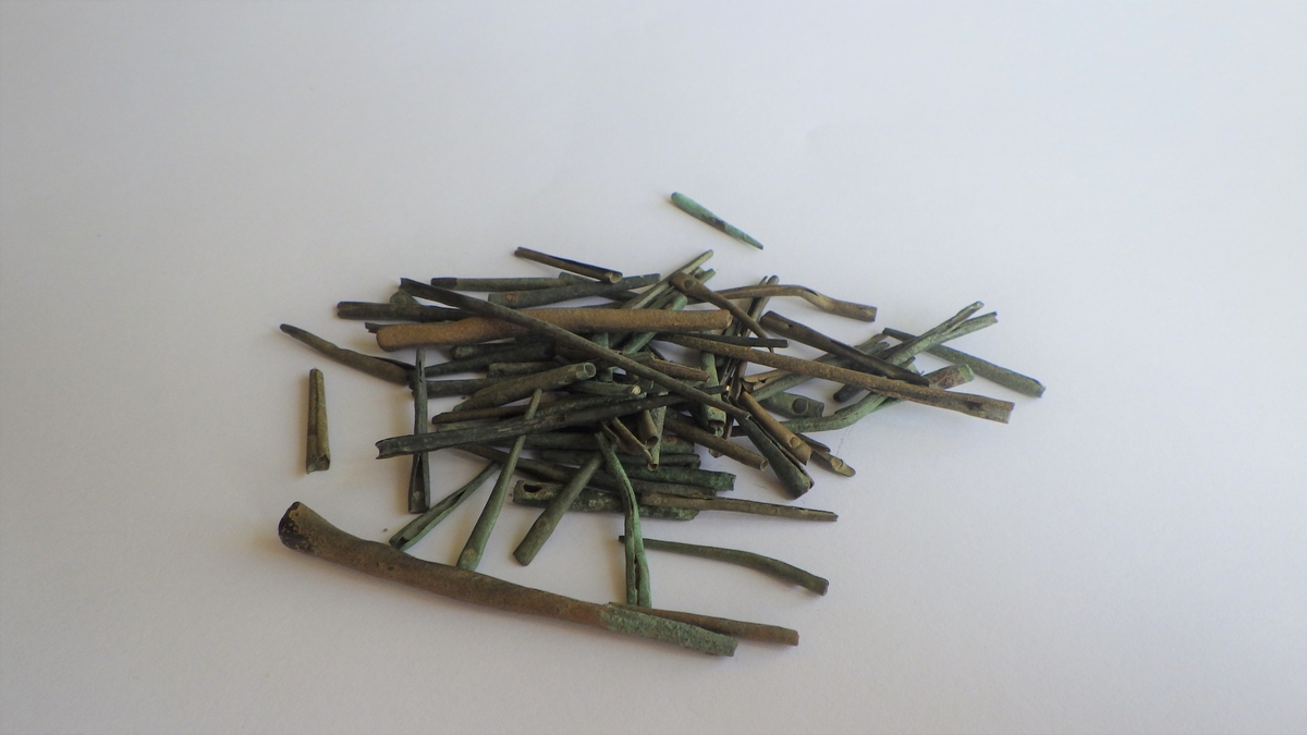 MALV: L. 20, 0-28, 8  ST. DIAM. CA. 3 MM, LAGET AV HAMRETE EMNER SOM ER RULLET SAMMEN TILHULE KJEGLEFORMETE BESLAG, 14 EKS. HAR ISITTENDE STIFT I VIDESTE ENDE, DE RESTERENDE HAR TYDELIG HULL FOR EN STIFT. REF. SE OPPGRAVNINGEN IN AMSTERDAM FIG. 182-185, DATERT FRA SLUTTEN AV1500-TALLET TIL FØRSTE HALVPART AV 1600-TALLET. 