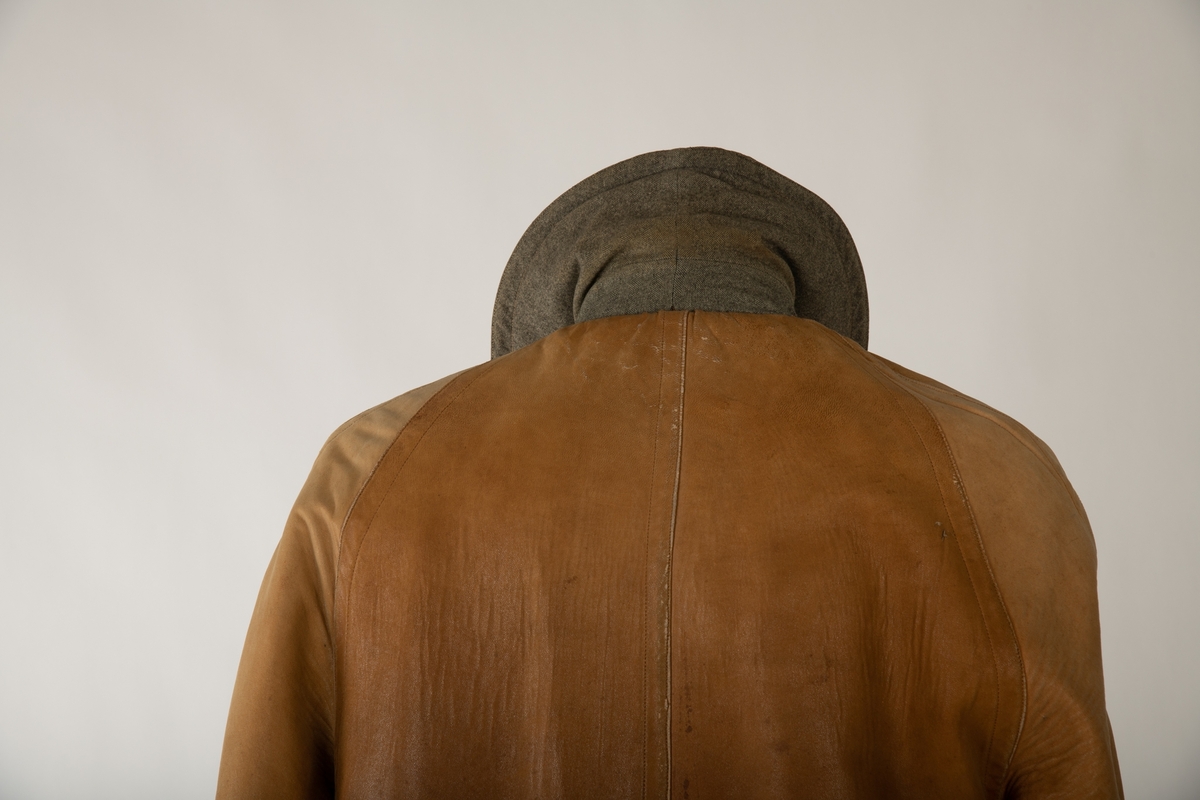 Dobbeltspennet frakk i lær og tweed. Frakken er sydd slik at den kan vrenges og brukes enten som en lærfrakk med foring av tweed eller en frakk av tweed med foring av lær. Begge sidene har opprinnelig fem knapper på hver side tillegg til to ved kragen, men lærsiden mangler en knapp på hver side. Begge har lommer med klaffer, en på høyre og en på venstre side. Begge har en splitt nederst på baksiden som kan kneppes igjen med tre knapper, lærsiden mangler en knapp. En bred krage i halsen er likedan slik at den fungerer på begge sider. I hver ermeende sitter to knapper på ene siden og to på andre, som gjør at ermet kan strammes inn med å feste på et bånd. Dette båndet sitter på siden som vender inn, men kan flyttes på. Et tilsvarende bånd sitter også ved kragen på den siden som vender inn. Det sitter i tillegg et metallhekte i kragen innerst ved halsen.