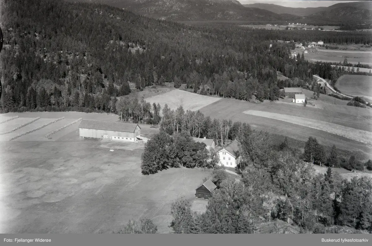 Skråfoto over gårder, skog og jorder. Avbildet gård er muligens Skollerud gård.