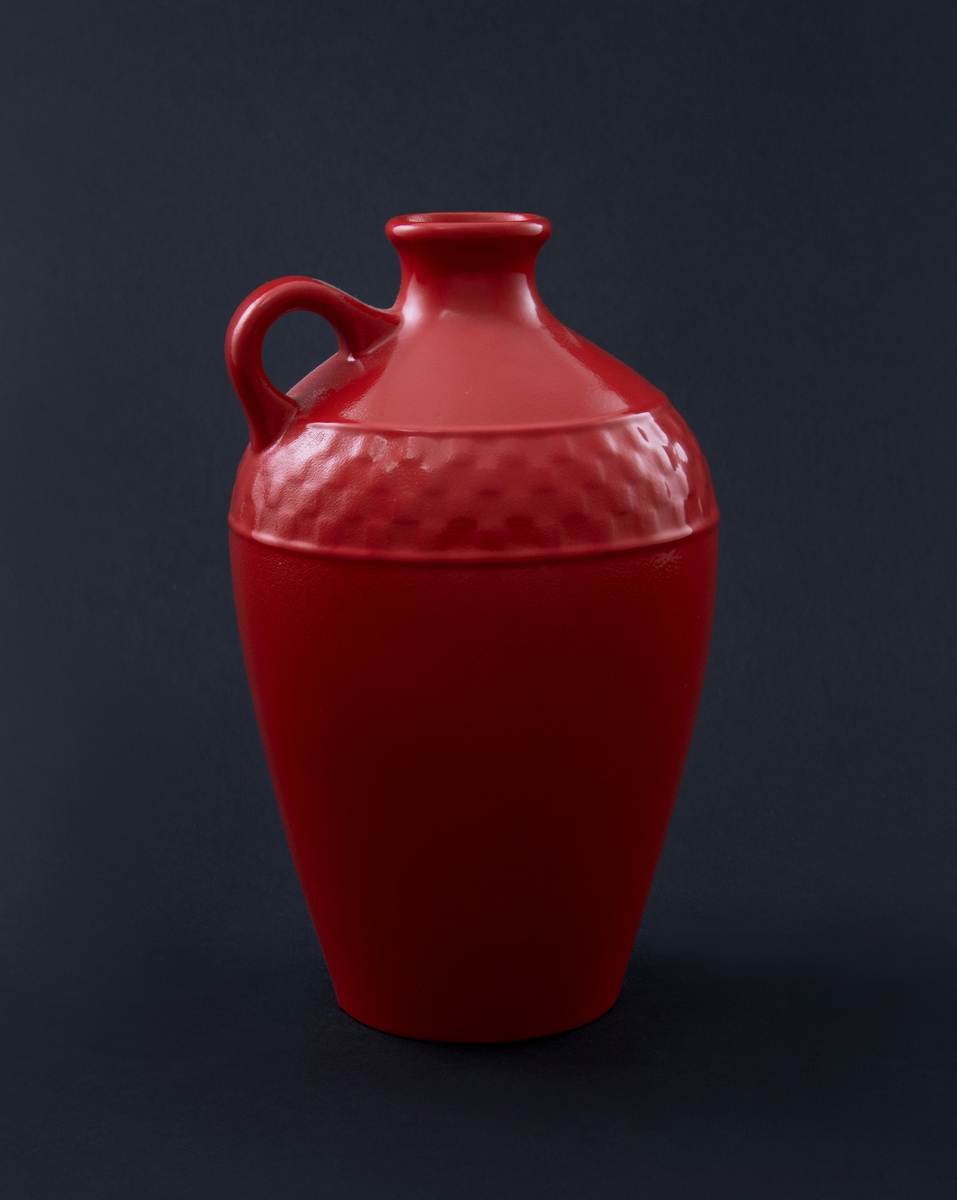 Rødlakkert keramisk vase. Brennvinskanneform med høyt korpus, liten hank og liten utbrettet munning. Sjakkmønster rundt skulder.  
Vasen er en readymade, altså et funnet objekt, som kunstneren har brennlakkert. Transformasjonen gjør at kun vaseformen står igjen, mens individuell glasur, farge og eventuelt motiv er gjemt bak den nye, monokrome, blanke overflaten. I følge kunstneren er de faktiske objektene funnet i antikvitetsbutikker og loppemarkeder, og er antakelig laget i løpet av de siste 100 år.