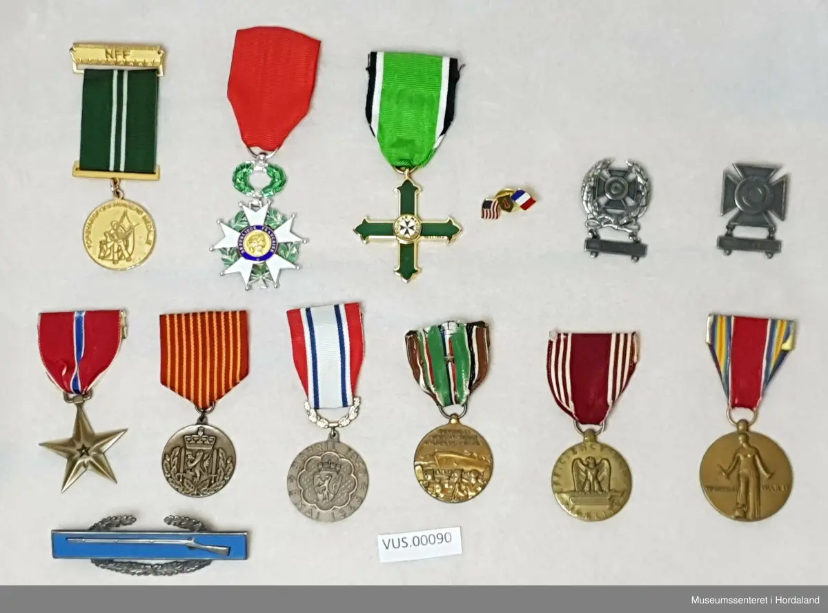 Ei samling med ni æresmedaljar og utmerkingar, og fire jakkemerker og merker som viser til ferdighet og tilhørighet til militær avdeling. 