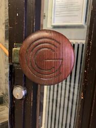 Dörrhandtag på CGC-huset med varuhusets loggotype som dekor,