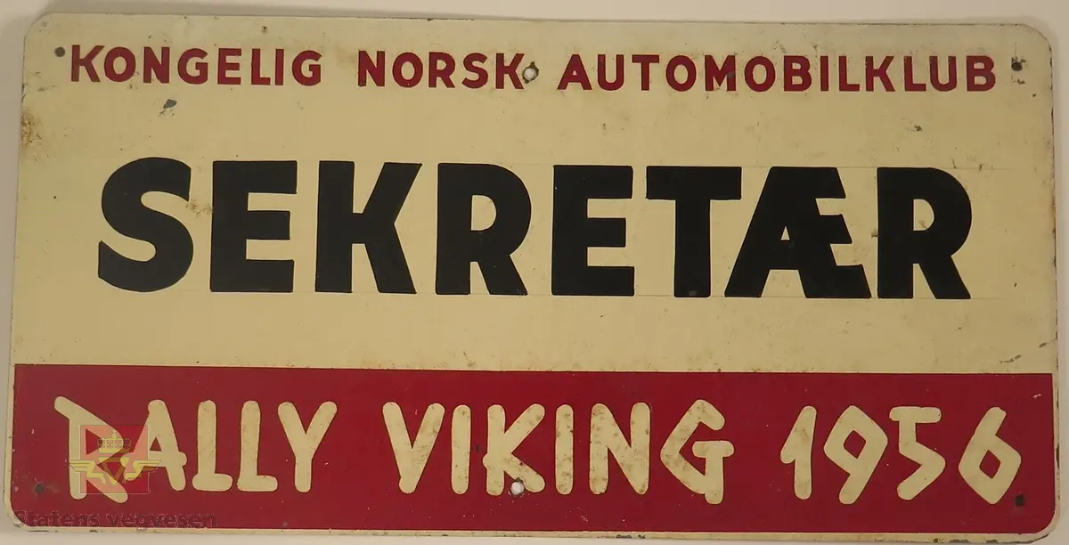 Hovedsakelig hvitt metallskilt med et mindre rødt markeringsområde. Det er laget til 6 festehull på skiltet, 3 nede og 3 oppe.
Påskrift: KONGELIG NORSK AUTOMOBILKLUB, SEKTRETÆR, K.N.A. RALLY VIKING
