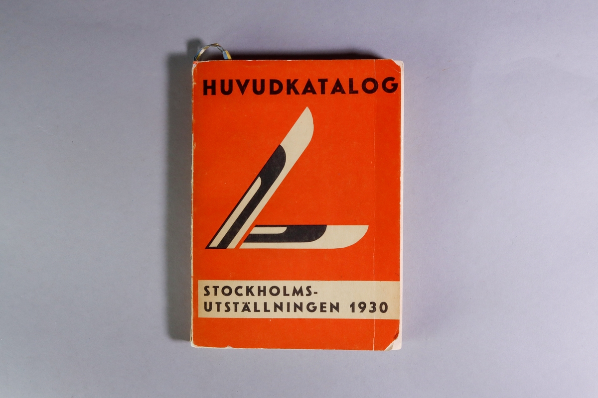 Utställningskatalog för Stockholmsutställningen 1930, huvudkatalog. Titel: "Stockholmsutställningen 1930 av konstindustri, konsthantverk och hemslöjd, maj-september : officiell huvudkatalog". Limhäftad katalog i enkelt pappband. 278 sidor med utvikbar karta över utställningsområdet. I ett inbundet blågult pappersband hänger ett bokmärke med reklam för falu rödfärg och trätjära från Stora Kopparbergslags aktiebolag Falun. Tryckt hos Almqvist & Wiksells Boktryckeri-A-B. Uppsala 1930.