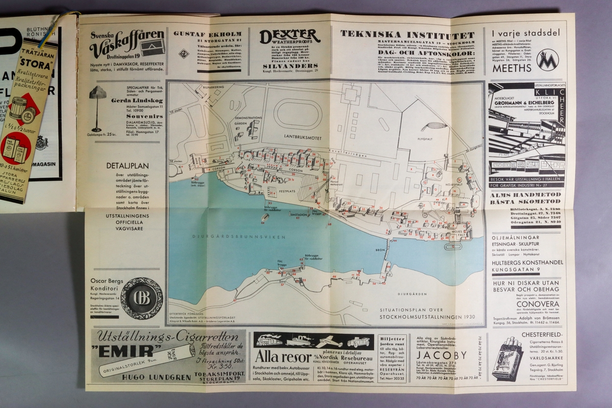 Utställningskatalog för Stockholmsutställningen 1930, huvudkatalog. Titel: "Stockholmsutställningen 1930 av konstindustri, konsthantverk och hemslöjd, maj-september : officiell huvudkatalog". Limhäftad katalog i enkelt pappband. 278 sidor med utvikbar karta över utställningsområdet. I ett inbundet blågult pappersband hänger ett bokmärke med reklam för falu rödfärg och trätjära från Stora Kopparbergslags aktiebolag Falun. Tryckt hos Almqvist & Wiksells Boktryckeri-A-B. Uppsala 1930.