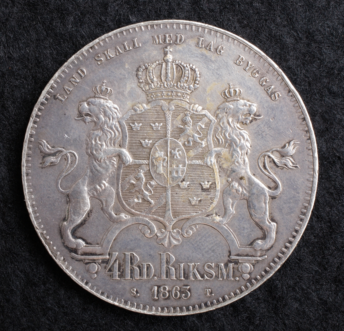 4 riksdaler riksmynt 1863. 
Regent: Karl XV 1859 - 1872.
Motiv: Konungens halsbild / krönta stora riksvapnet.
Omskrift: CARL XV SVERIGES NORR. GÖTH. OCH VEND. KONUNG.
Gravör: Lea Ahlborn.
Myntmästare: Sebastian Tham.
Konstnär:
Rand: Nedsänkt text: 75/100 DELAR FINSILFVER.
Diameter: 39 mm.
Stämpelställning: 0 grader.
Myntfakta/Kommentar: Punkter mellan L. A.
Proveniens:
Vikt: 33,9 gram.
Litteratur: SM 16.