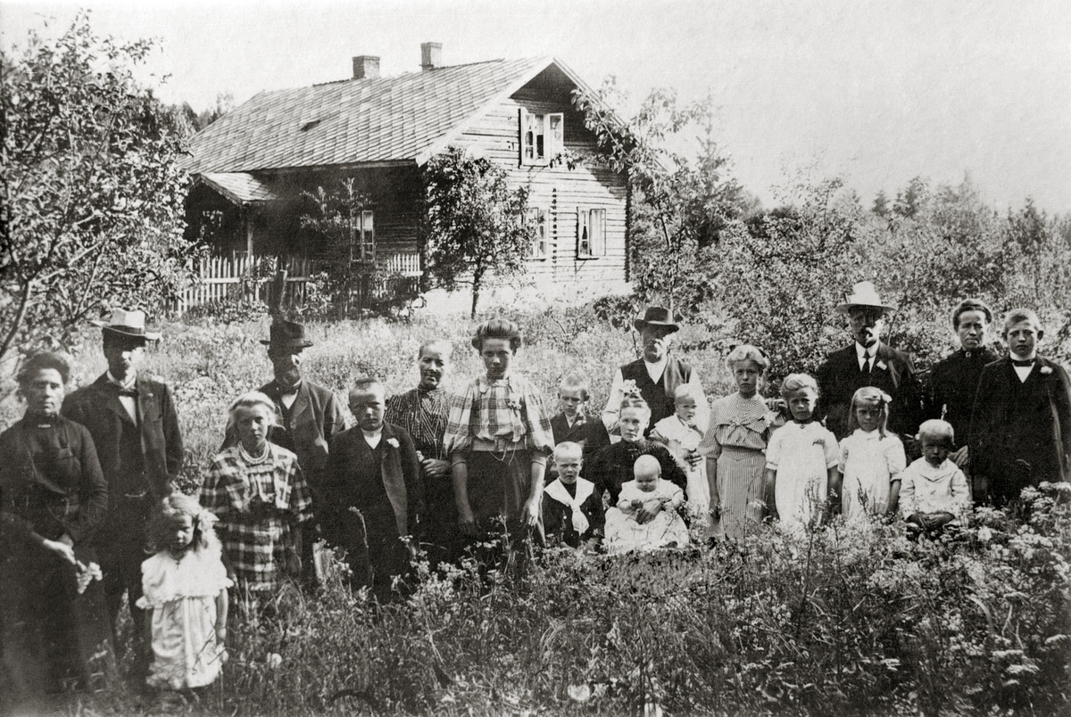 Familiegruppe.
Bildet er fra Løkkekværn Gård. Kvinnen som sitter med et barn på fanget er Gunda Amalie Prestkværn. Hennes mann Kristian står bak. Barna nærmest dem er antagelig deres barn Ole, Einar, Kolbjørn og Martha. Håkon er yngst og født i 1908, og er ikke med på bilde. så dermed kan en anta at bildet er fra før 1908.
De andre kvinnene på bildet antas å være Kristians søstre med familier. Ytterst til venstre Jørgine Olsdatter, hennes mann Iver Haugen og deres datter Kirsten f.1905. Mellom disse og Kristian m.familie står Antonette Olsdatter Hindklev med sin mann Børre Hindklev og deres barn Kristine, Ole og Klara.  Til høyre finner vi Mart(h)e Olsdatter Grøndal, hennes mann Iver Grøndal, døtrene Kristine, Odrun og Alma og sønnene Peder (yngst) og Iver Magne.