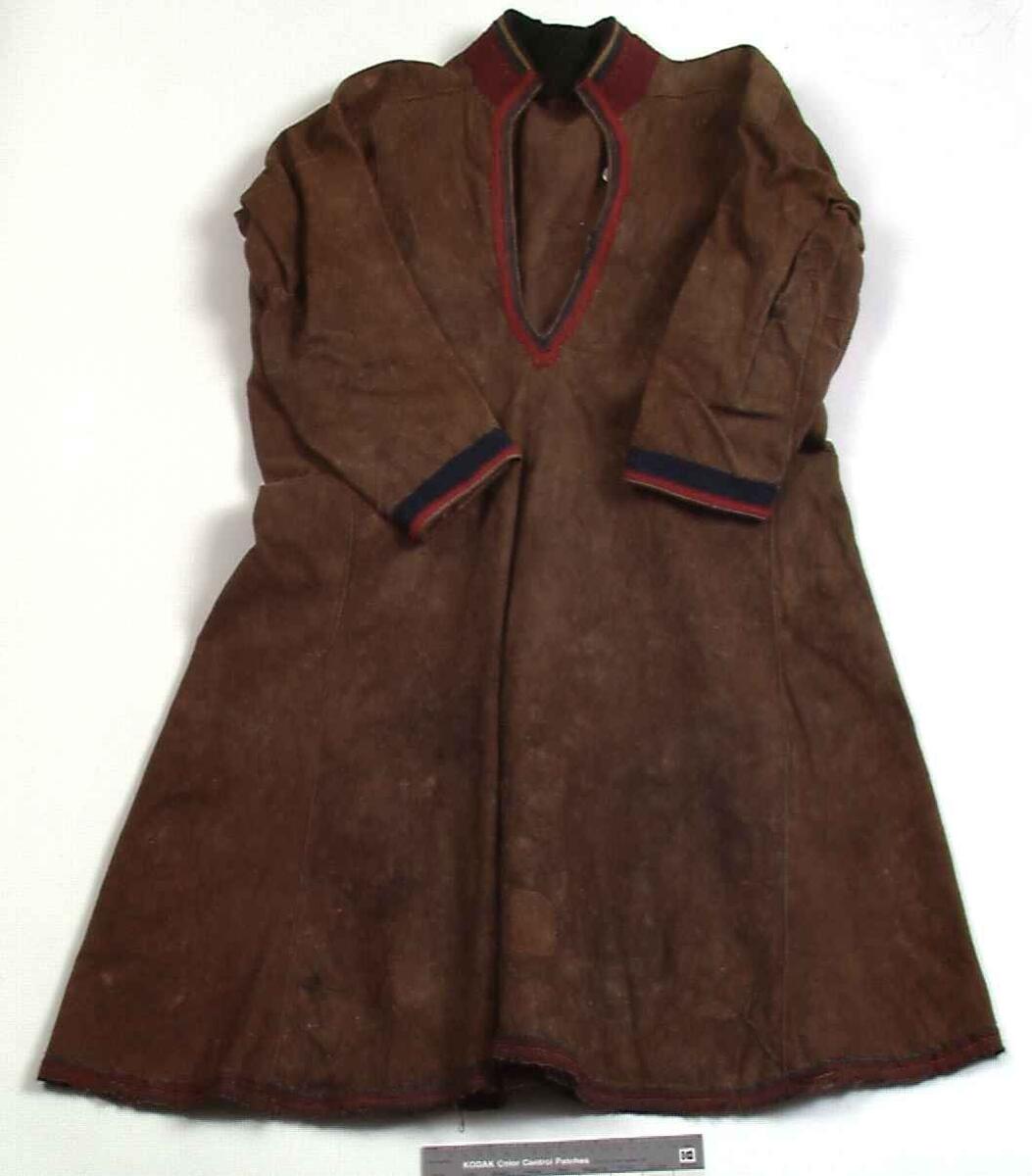 Sválltjá/kinnkofte med tekstilapplikasjoner og grindvevd pyntebånd. Goahkka/Krage i vinrød bunnfarge, uten divlle, men dekor øverst i grønt og gult. Badjelbuttas i goahkka/krage er mørkeblå. Åhtså med sájá i rødt og blått. Sase/ermedekor med sájá i blått og rødt og med badjelbuttas i brunt skinn. Nederst påsydd snjisjkodum/vevd lissto/kantband.