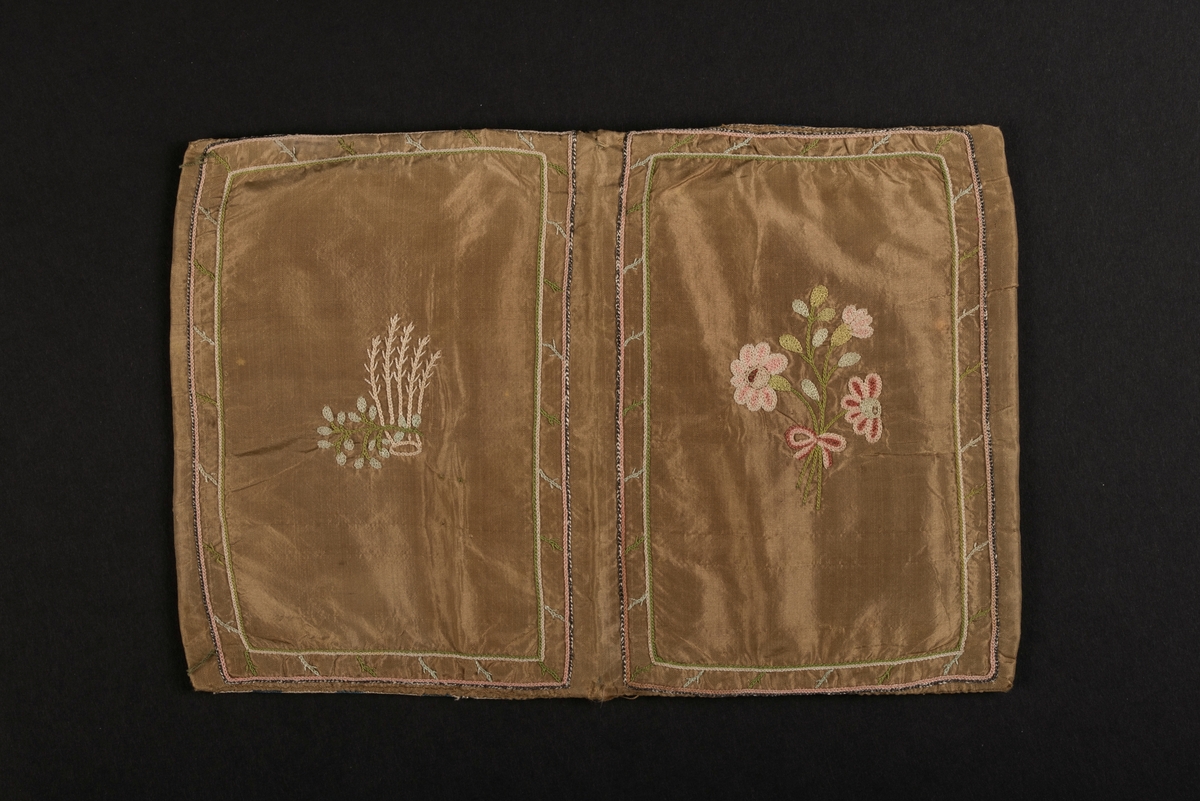 Plånbok, även kallad sedelbok, med två fack, av siden. 
Dekorerad med broderier av silkestråd i kedjesöm. Det bruna sidentyget har broderade kantbåder. På utsidorna blomsterbroderier och på insidan blomsterbroderi på ett av de två facken. På det andra facket finns en broderad text inom ram: Minne af Vreta Kloster d: 24 Dec 1792.