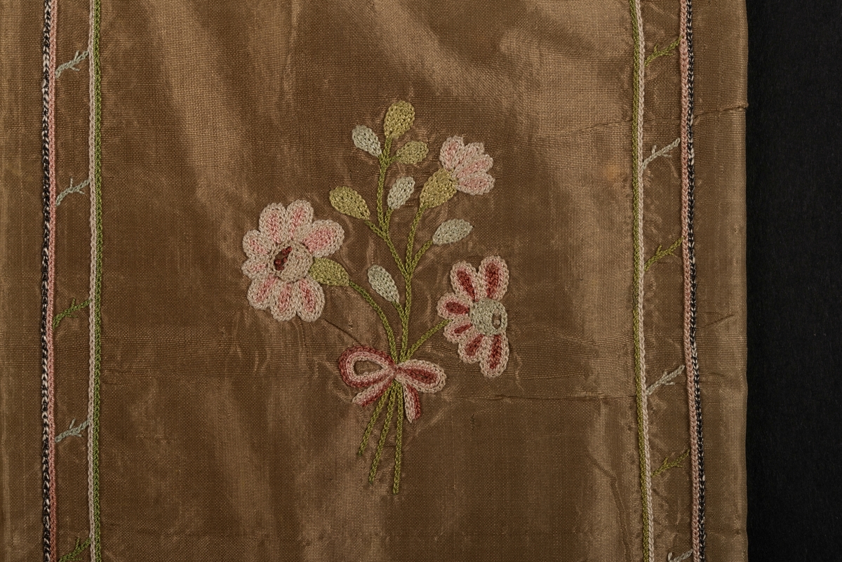 Plånbok, även kallad sedelbok, med två fack, av siden. 
Dekorerad med broderier av silkestråd i kedjesöm. Det bruna sidentyget har broderade kantbåder. På utsidorna blomsterbroderier och på insidan blomsterbroderi på ett av de två facken. På det andra facket finns en broderad text inom ram: Minne af Vreta Kloster d: 24 Dec 1792.