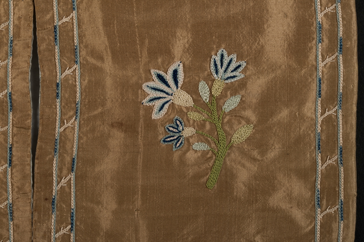 Plånbok, även kallad sedelbok, med två fack, av siden. 
Dekorerad med broderier av silkestråd i kedjesöm. Det bruna sidentyget har broderade kantbåder. På utsidorna blomsterbroderier och på insidan blomsterbroderi på ett av de två facken. På det andra facket finns en broderad text inom ram: Minne af Vreta Kloster d: 24 Dec 1792.