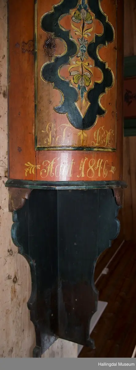 Høgseteskåp fra Åsen i Nes. .
Rosemalt hjørneskap som er rundet framme. Brunrød bunn med gul skrift.  Svartmalt ramme inni utskjæring på døra.  Inni rammen er det en grein som går opp og en grein som går rett ned med likesidet blomster malt i blått, gult, grønt hvitt og svart. 3 greiner med blå gule og hvite blomster øverst på skapet ovom døra.  Nøkkel i låsen. Inni skapet er det 3 hyller, bare den i midten er opprinnelig og gammel. Skapet står på en "pillar" uten hyller.  Det er profilerte utskæringer øverst, danner et omvendt hjerte i toppen.  Skapet er listet øverst i en bue og nede.  Listen er malt mørk grønn/blå med "gullkant" inn mot skapet. Profilene er malt med "gullfarge".