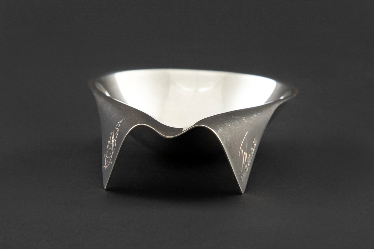 Pipestativ i sølv. Dråpeformet skål som smalner sammen til en forlenget endeparti med to nedbrettede kantfolder med monogram.