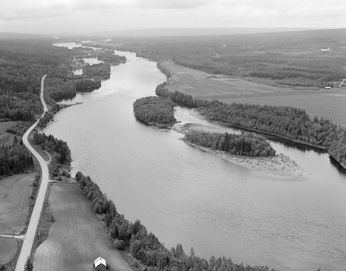 Flyfotografi, tatt over Glomma i Elverum. Bildet er tattlike nedenfor Letjernas innløp i hovedvassdraget med kameraet vendt sørover. Jordbruksarealene til venstre i forgrunnen tilhører eiendommen Svanåsen, mens åkrene til høyre tilhører garden Sætersmoen. Følgelig er det Sætersmoøya vi ser i den vestre delen av elveløpet og Kvernbakkøya ved østre elvebredd, lengre nede. Vi ser også ned på Strandbygdvegen.