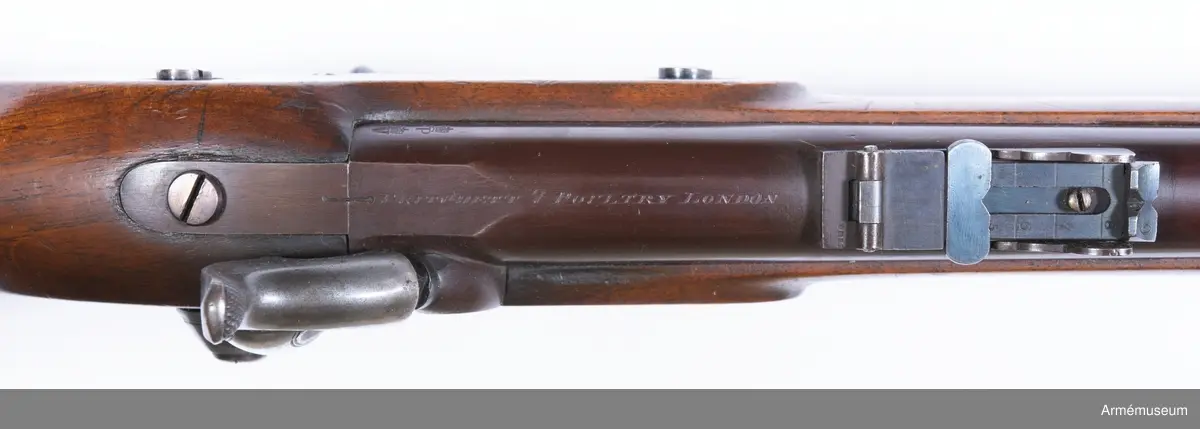 Grupp E II.
Gevär med slaglås.
Antal räfflor: 3. Räffelstigning: ett halvt varv på piplängden. Kulvikt: 34 g. Krutladdningens vikt: 4 g. Pipan är brungjord och rund, men har baktill på översidan en 3,5 cm lång avplattning. Snäckan är rätt liten. En fyrkantig kombinerad bajonett- och kornklack sitter 3,3 cm bakom mynningen och på översidan av denna klack sitter det orörliga kornet. Ramtrappsiktets fot sitter 8,9 cm framför pipans bakre ände. Siktet har gradering för avstånd mellan 100 och 900 yards= resp 90 och 810 m. På pipans översida står PRITCHETT 7 POULTRY LONDON och på vänstra sidan är två Londonstämlar inslagna.

På det gråhärdade, framåtliggande kedjelåset är hanen och låsblecket längs kanterna prydda med ett par ingraverade ränder. stocken är av valnöt. Framstocken har en avsats för vart och ett av de tre banden. Piprännan är utvidgad alldeles bakom näsblecket. Bakplåten och varbygeln är av mässing. Den förstnämnde har en ganska lång, smal flik, som går in över kolvryggen och som längst fram är fäst med en skruv, under det att två skruvar sitter i bakplåten. Geväret har egentligen ej sidbleck, utan kring vart och ett av de bägge hålen för låsskruvarna finns en smal, ringliknande mässingsskoning, från vilken en kort arm går framåt och en annan bakåt. De tre banden är av gråhärdat järn och ha på undersidan öron, som förenas genom en skruv. Det främsta bandet ligger 8 cm bakom stockens framände och skruven på detta band fasthåller den främre rembygeln. Näsblecket är av mässing, och fasthålles av en underifrån kommande skruv. Den bakre rembygeln är fäst i varbygelns främre del.

Laddstocken är av stål och har skålformigt huvud. Omkring 12 cm från framänden har laddstocken en ungefär 2,5 cm lång förtjockning, som passar i laddstocksrännans ovan omtalade utvidgning. I smaländen är laddstocken gängad på en längd av 0,8 cm. Litet bakom huvudet finns fyra nästan utslipade bokstäver (R & K?).

Om den till detta gevär använda ammunitionen, se AM 6117-6120. Uppgiften om reffelstigningen har hämtats ur Jochnick, Handgevärslära, Stockholm 1863 paragraf 60. Geväret kallas vanligen Enfield- pritchetgeväret, då det konstruerades av gevärsfabrikanten Pritchett och antogs av den i Enfield församlade gevärskommiten. Av allt att döma har alltså den ovan beskrivna gevär tillverkats av konstruktören.