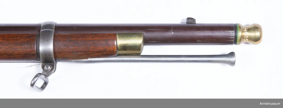 Grupp E II.
Gevär med slaglås.
Antal räfflor: 3. Räffelstigning: ett halvt varv på piplängden. Kulvikt: 34 g. Krutladdningens vikt: 4 g. Pipan är brungjord och rund, men har baktill på översidan en 3,5 cm lång avplattning. Snäckan är rätt liten. En fyrkantig kombinerad bajonett- och kornklack sitter 3,3 cm bakom mynningen och på översidan av denna klack sitter det orörliga kornet. Ramtrappsiktets fot sitter 8,9 cm framför pipans bakre ände. Siktet har gradering för avstånd mellan 100 och 900 yards= resp 90 och 810 m. På pipans översida står PRITCHETT 7 POULTRY LONDON och på vänstra sidan är två Londonstämlar inslagna.

På det gråhärdade, framåtliggande kedjelåset är hanen och låsblecket längs kanterna prydda med ett par ingraverade ränder. stocken är av valnöt. Framstocken har en avsats för vart och ett av de tre banden. Piprännan är utvidgad alldeles bakom näsblecket. Bakplåten och varbygeln är av mässing. Den förstnämnde har en ganska lång, smal flik, som går in över kolvryggen och som längst fram är fäst med en skruv, under det att två skruvar sitter i bakplåten. Geväret har egentligen ej sidbleck, utan kring vart och ett av de bägge hålen för låsskruvarna finns en smal, ringliknande mässingsskoning, från vilken en kort arm går framåt och en annan bakåt. De tre banden är av gråhärdat järn och ha på undersidan öron, som förenas genom en skruv. Det främsta bandet ligger 8 cm bakom stockens framände och skruven på detta band fasthåller den främre rembygeln. Näsblecket är av mässing, och fasthålles av en underifrån kommande skruv. Den bakre rembygeln är fäst i varbygelns främre del.

Laddstocken är av stål och har skålformigt huvud. Omkring 12 cm från framänden har laddstocken en ungefär 2,5 cm lång förtjockning, som passar i laddstocksrännans ovan omtalade utvidgning. I smaländen är laddstocken gängad på en längd av 0,8 cm. Litet bakom huvudet finns fyra nästan utslipade bokstäver (R & K?).

Om den till detta gevär använda ammunitionen, se AM 6117-6120. Uppgiften om reffelstigningen har hämtats ur Jochnick, Handgevärslära, Stockholm 1863 paragraf 60. Geväret kallas vanligen Enfield- pritchetgeväret, då det konstruerades av gevärsfabrikanten Pritchett och antogs av den i Enfield församlade gevärskommiten. Av allt att döma har alltså den ovan beskrivna gevär tillverkats av konstruktören.