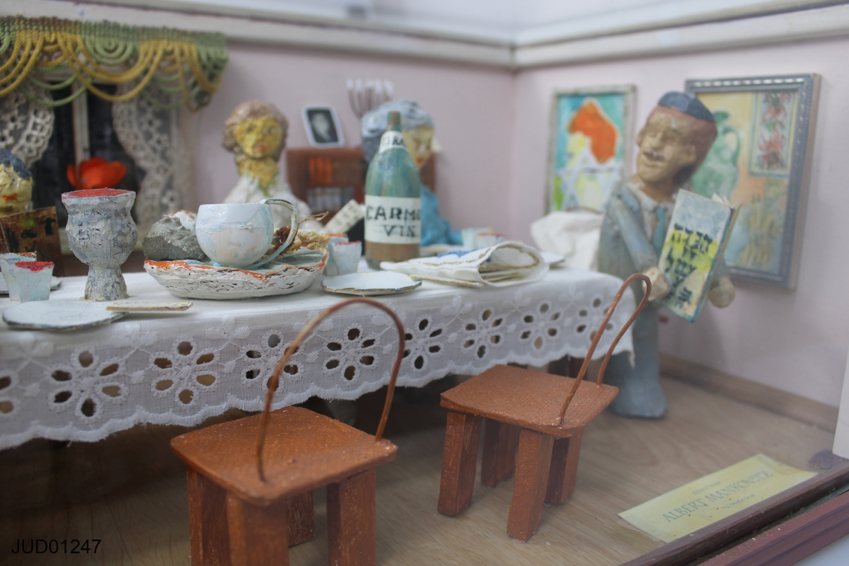 Pesachscen med dockor i glasmonter, betitlad "Sedermåltid i hemmet".