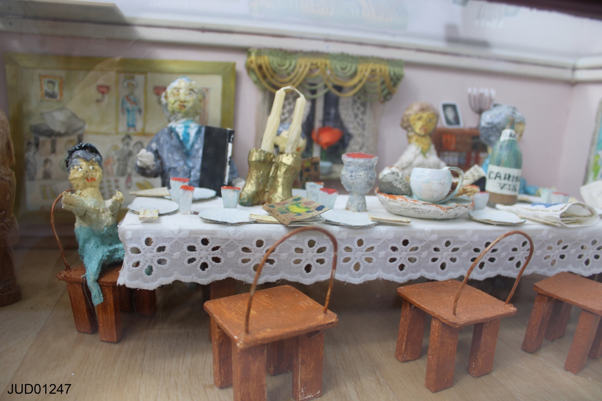 Pesachscen med dockor i glasmonter, betitlad "Sedermåltid i hemmet".