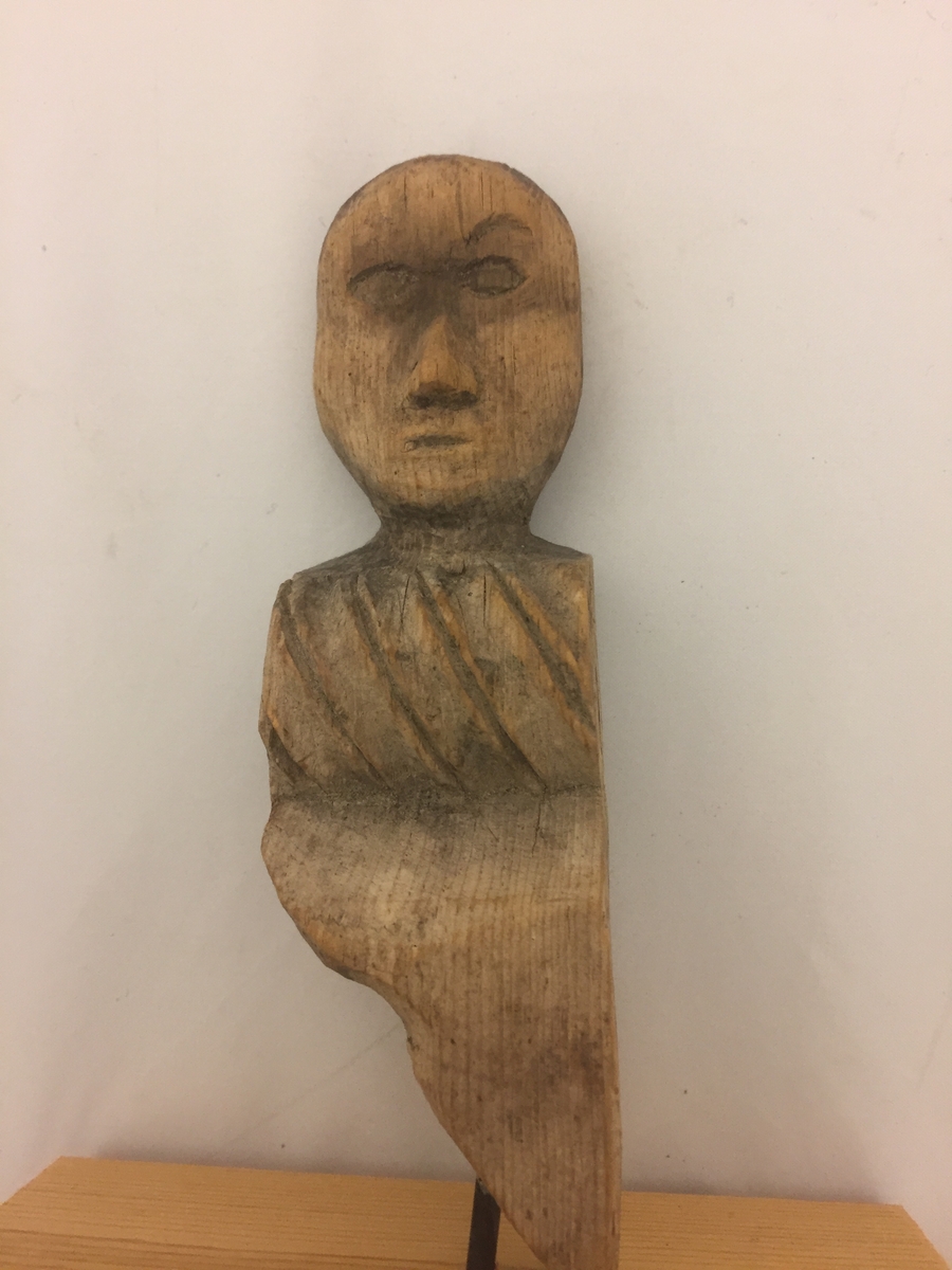 Liten figur forma som eit mannshovud, Kloss sett på i seinare tid, festa med spiker. Denne er fjerna, men figuren har hol i botn etter spikeren.