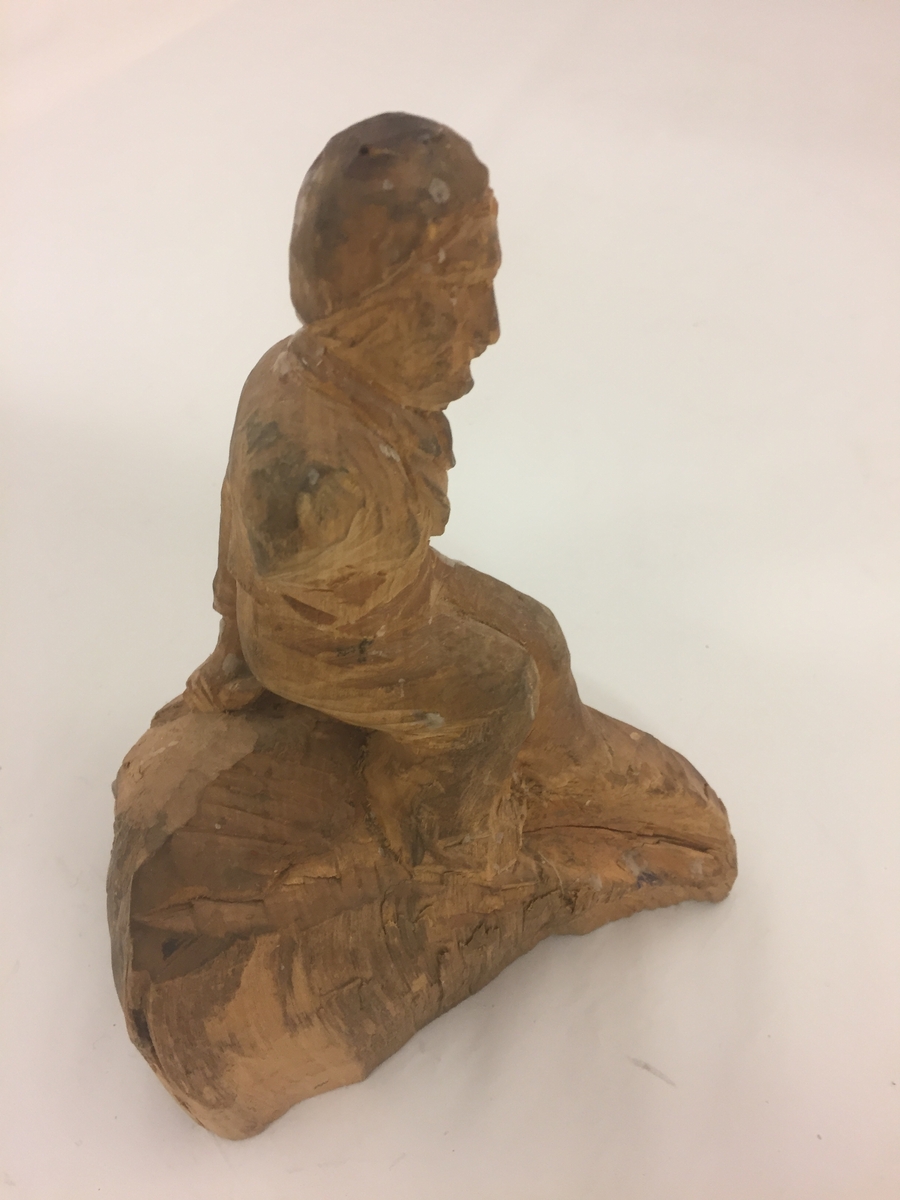 Sitjande mannsfigur.