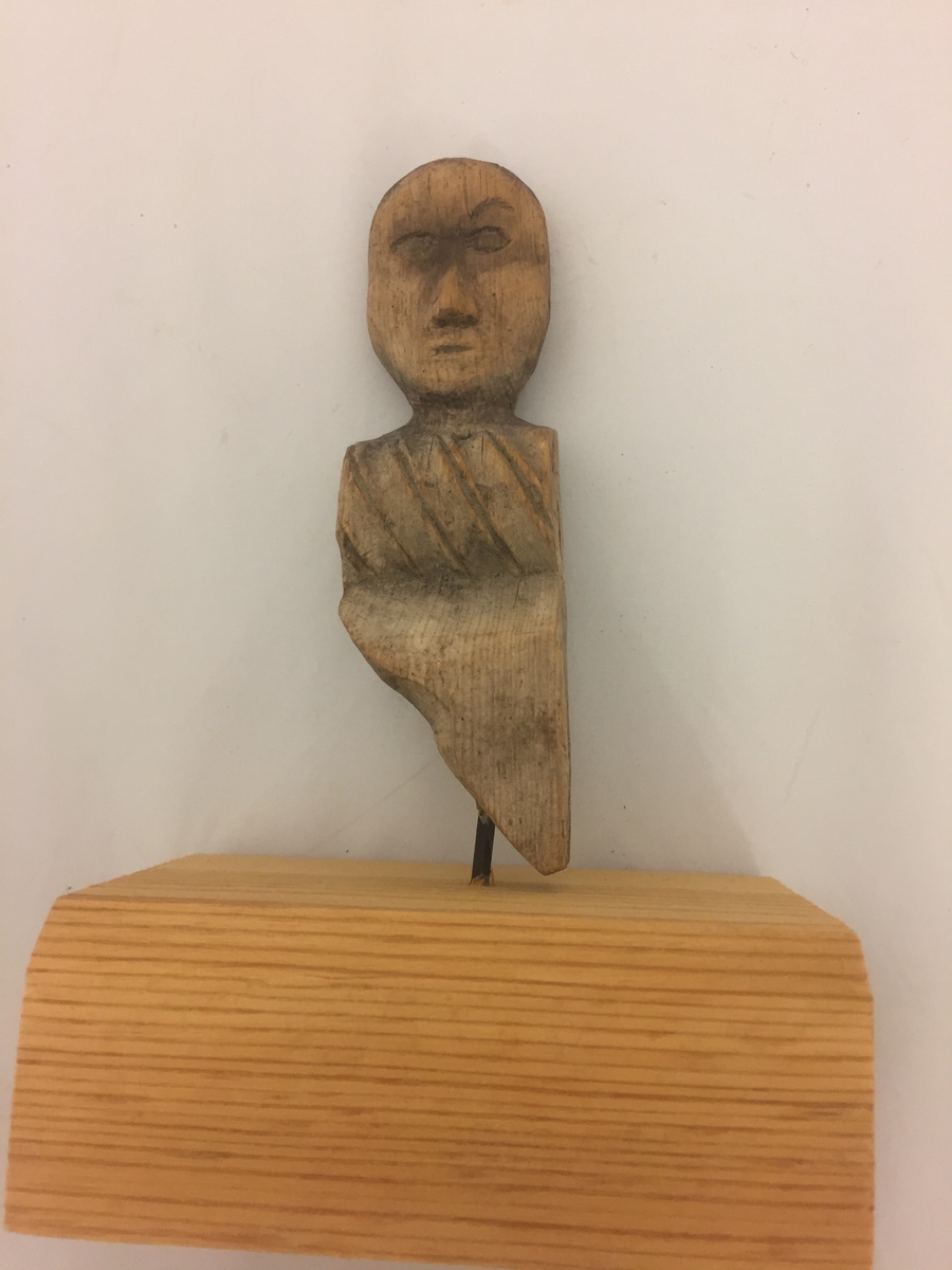 Liten figur forma som eit mannshovud, Kloss sett på i seinare tid, festa med spiker. Denne er fjerna, men figuren har hol i botn etter spikeren.