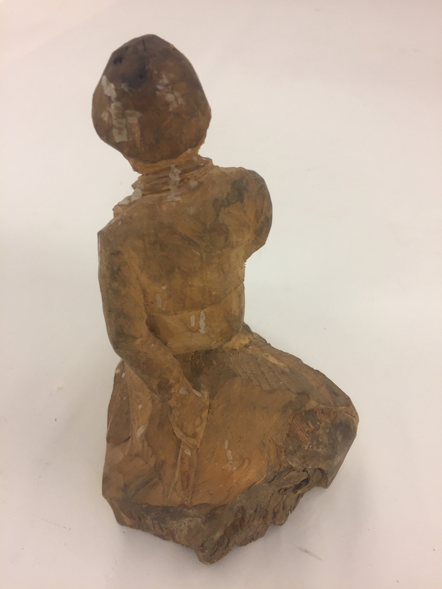 Sitjande mannsfigur.