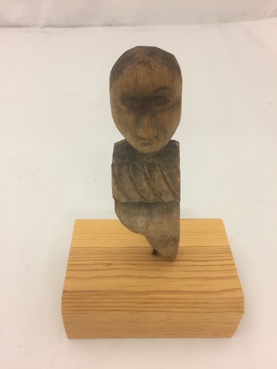Liten figur forma som eit mannshovud, Kloss sett på i seinare tid, festa med spiker. Denne er fjerna, men figuren har hol i botn etter spikeren.