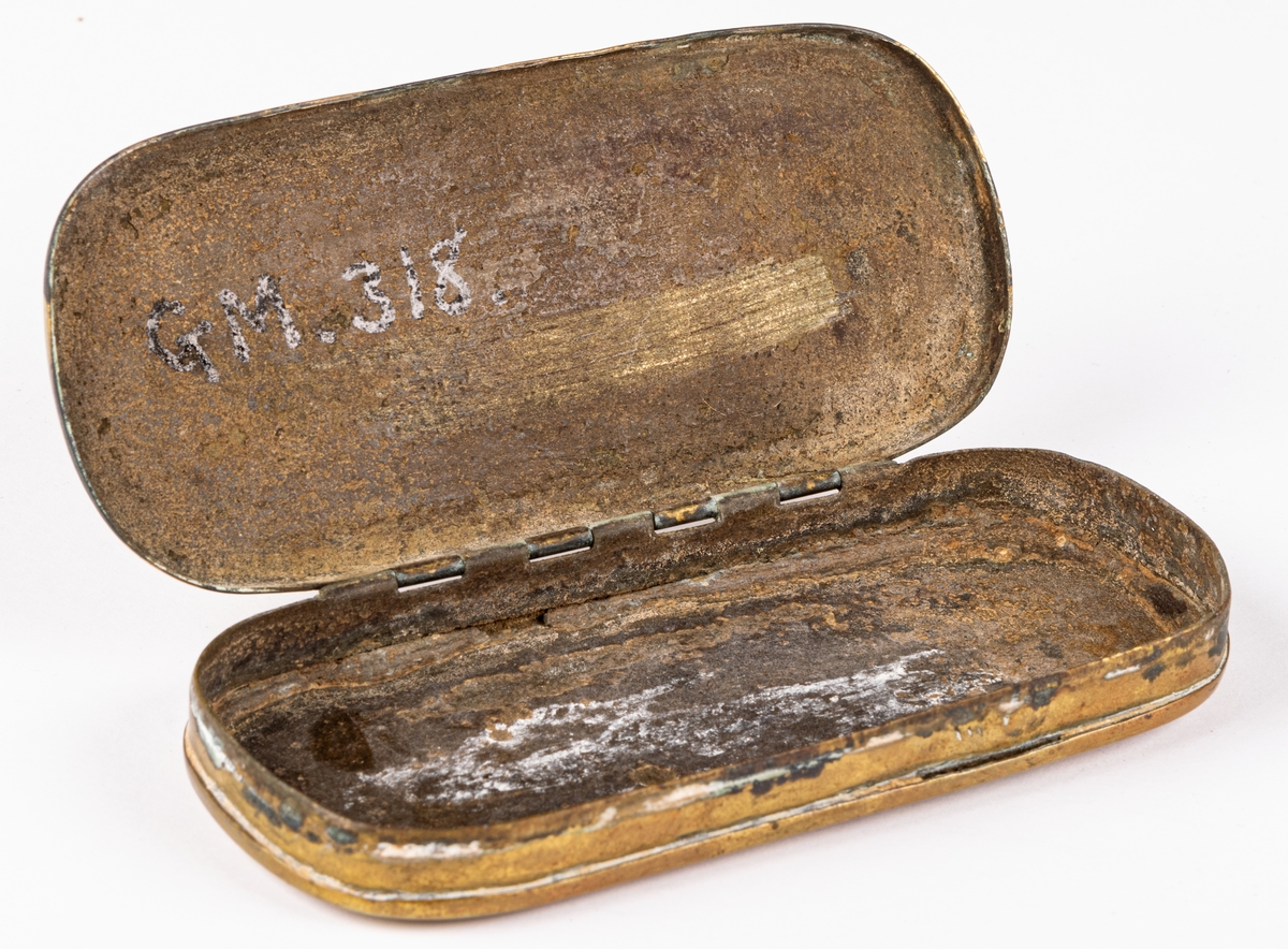 Snusdosa, av mässing, avlång, platt, med almanack i relief på sidorna. Mycket sliten.