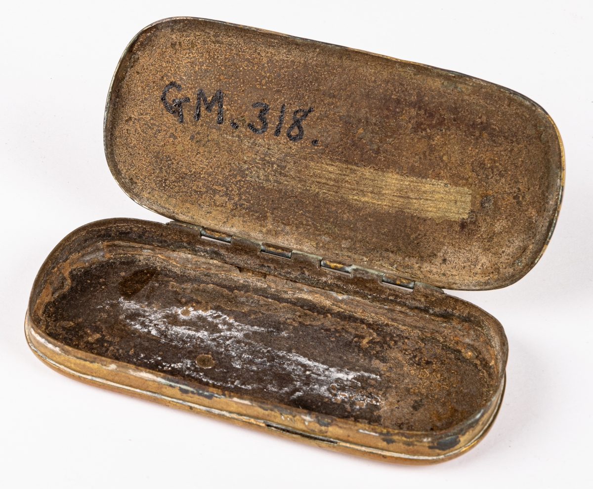 Snusdosa, av mässing, avlång, platt, med almanack i relief på sidorna. Mycket sliten.