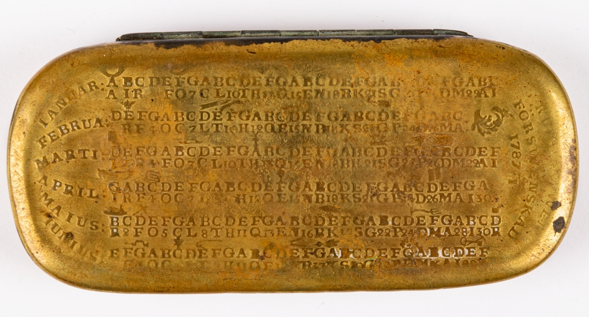 Snusdosa, av mässing, avlång, platt, med almanack i relief på sidorna. Mycket sliten.