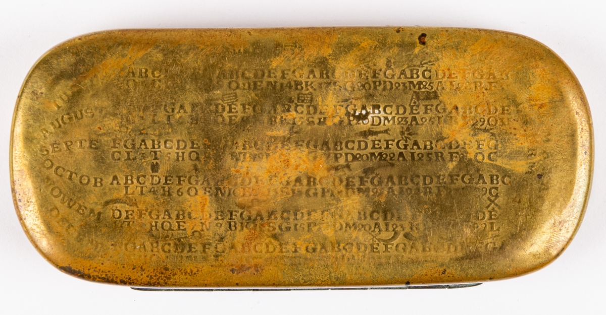 Snusdosa, av mässing, avlång, platt, med almanack i relief på sidorna. Mycket sliten.