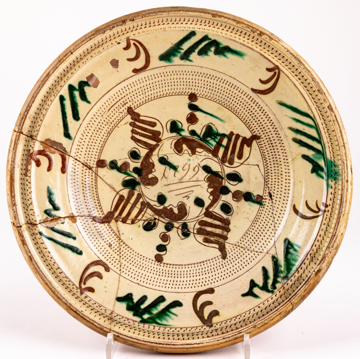 Lerfat, invändigt glaserat i gult, dekor i brunt och grönt. 1799, spräckt.