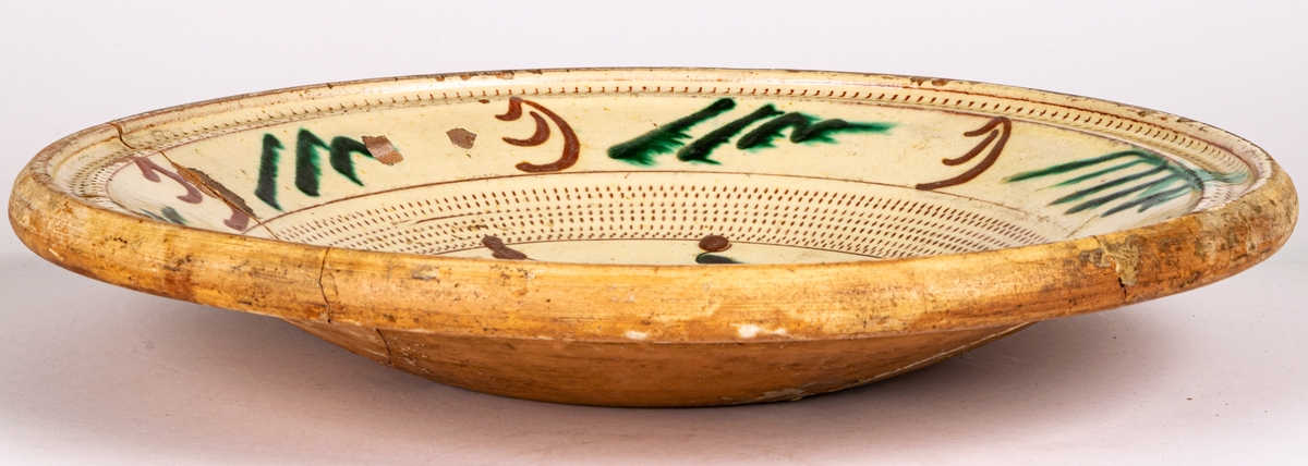 Lerfat, invändigt glaserat i gult, dekor i brunt och grönt. 1799, spräckt.