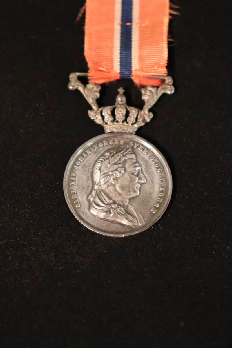Med krone og sløyfe.
Side 1. er det skrevet Carl XIV Johan Norges Sver.g. og V. Konge.
Side 2. For Borgerdaad. (omkranset av laurbær).