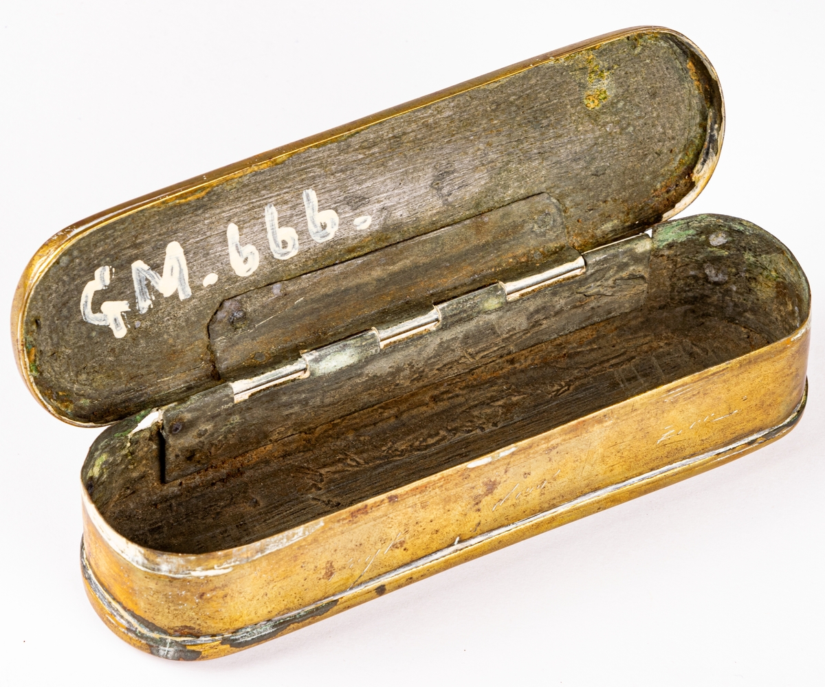 Snusdosa, av mässing, platt, avlång, med almanackor ristade på sidorna.